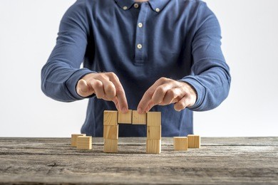 front view of a man making a bridge with wooden cubes. conceptual of business, education and construction.