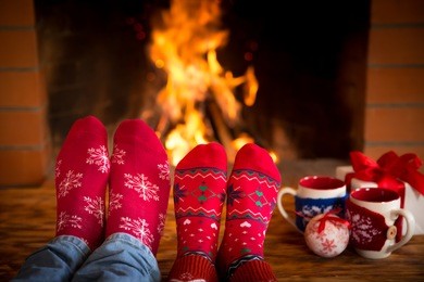 couple relaxing at home. feet in christmas socks near fireplace. winter holiday concept