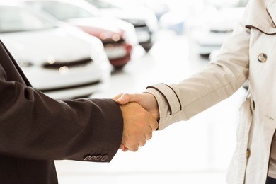 salesman shaking a customer hand at new car showroom
