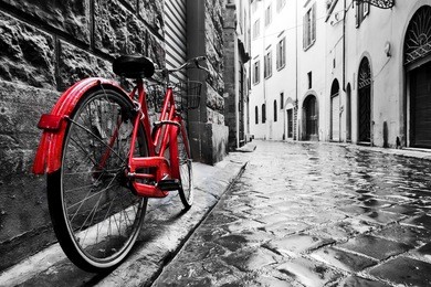 retro vintage red bike on cobblestone street in the old town. color in black and white. old charming bicycle concept.