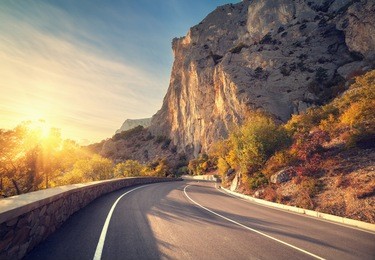 asphalt road in autumn forest at sunrise. crimean mountains.