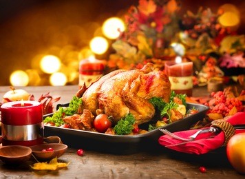 roasted turkey. thanksgiving table served with turkey, decorated with bright autumn leaves and candles. roasted chicken, table setting. christmas dinner 