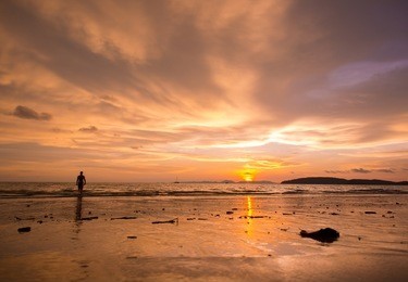 一位年轻女性在日落时站在泰国甲米奥南海滩享受假期