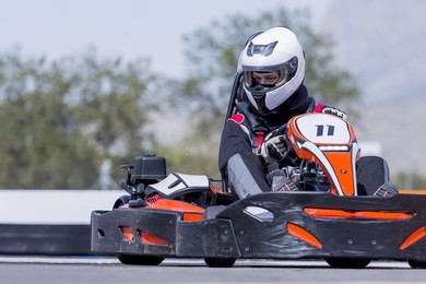 young man go-kart pilot is racing a race in an outdoor go