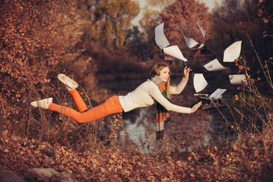 woman writer levitation in the autumn forest near lake. concept of freedom and independence in the work
