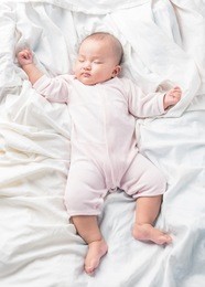 asian sleeping baby on back on white bed