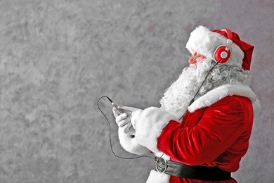 santa claus with headphones listening to music on gray wall background