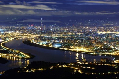 aerial panorama of taipei city in a blue gloomy night, with view of kuandu  plain, tamsui river, downtown area and taipei 101 tower in xinyi district, in evening twilight