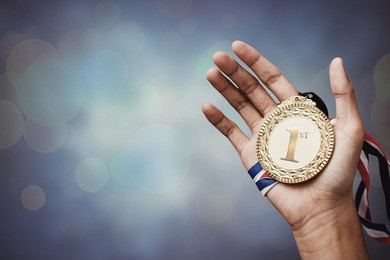 hand holding up a gold trophy cup as a winner in a competition