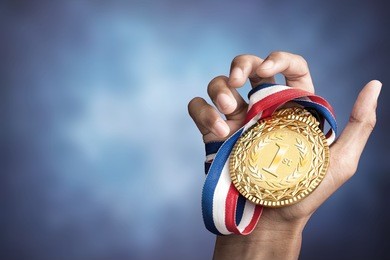 hand holding up a gold trophy cup as a winner in a competition