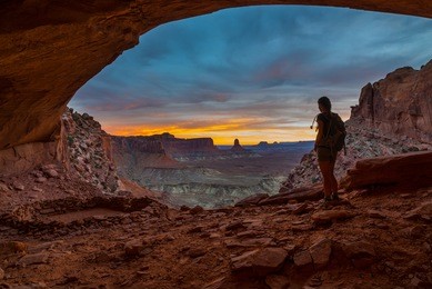 girl backpacker looking at beautiful sunset from inside of the false kiva canyonlands national park moab utah usa