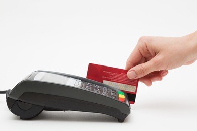 hand swipe red credit through payment terminal 
