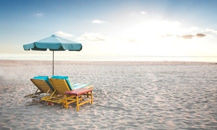 a portrait of a pair of beach chair with umbrella in a seashore