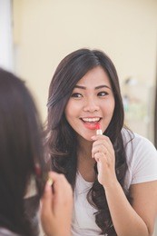 portrait of woman applying red lipstick on her lips
