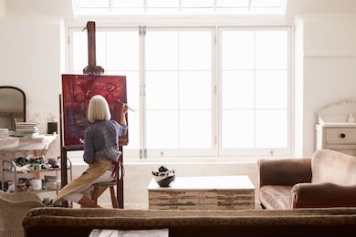 female artist working on painting in bright daylight studio