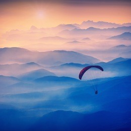 paraglide silhouette in a light of sunrise above the misty crimea valley. vintage colors