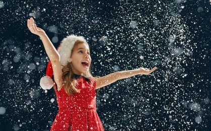 a christmas miracle! happy little girl catching snowflakes in her hands