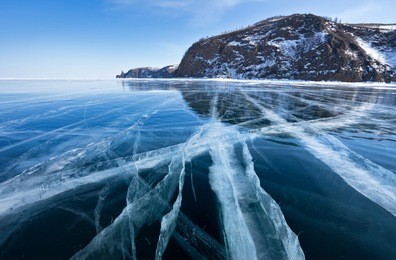lake baikal in winter day. cracks on the smooth surface of the ice near the cliffs of olkhon island