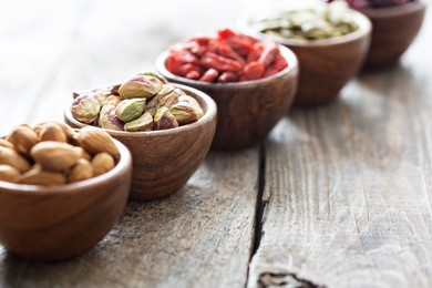 variety of nuts and dried fruits in small wooden bowls