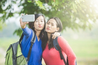 a portrait of two young asian students taking selfie, happily