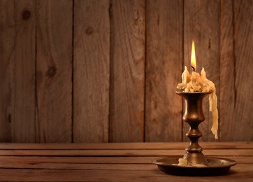 burning old candle vintage bronze candlestick on wooden background. 
