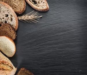 bread slices, a wheat and a knife on the black stone desk.