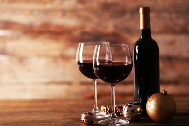red wine and christmas ornaments on wooden table on wooden background