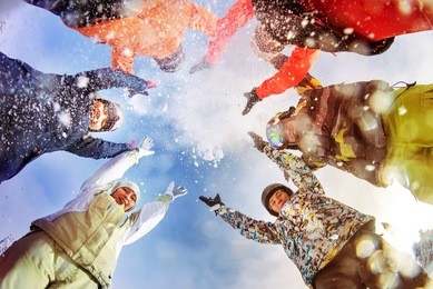 group of happy snowboarders and skiers having fun and throwing up snow