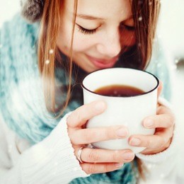 young beautiful female drinking hot drink outdoors in winter. close up headshot. drawn snow. selective focus. instagram color effect.