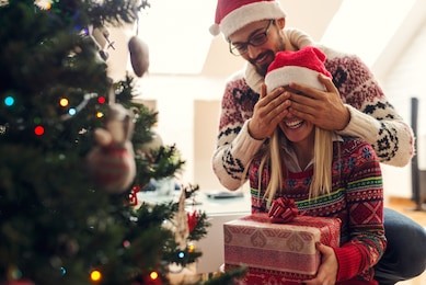  cropped shot of a man surprising his girlfriend with a christmas gift.