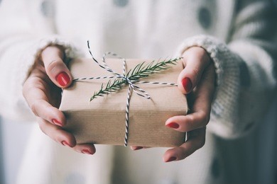 woman's hands hold christmas or new year decorated gift box. toned picture