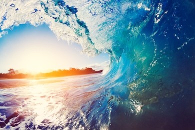 blue ocean wave crashing at sunrise