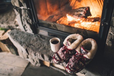 christmas comfortable slippers by the warm cozy fireplace. relaxing atmosphere in a chalet by authentic vintage fireside with a cup of hot drink. winter and christmas holidays concept.
