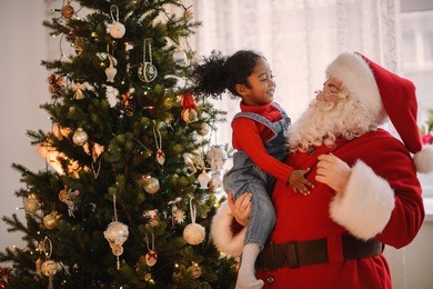 santa claus playing with cute african american child at home
