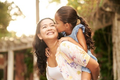 woman giving piggyback ride to her daughter