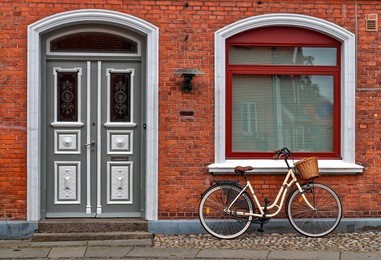 yellow bicycle parked in front of red old house in denmark
