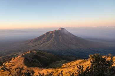 stunning sunrise over the merapi volcano and the countryside around yogyakarta in central java in indonesia from the top of the merbabu volcano.