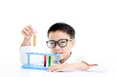 young asian boy in white shirt wearing eyeglass doing experiments with color solution in small tube at the lab.