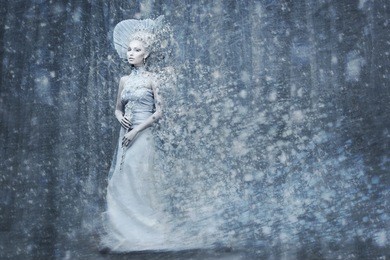 beautiful young woman. fairy tale snow queen in silver dress and crown with staff in magic forest. copy space.