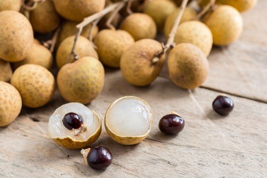 longan fresh (dimocarpus longan.)a bunch of longan and peel show the white meat with black seed was placed on a wooden background.