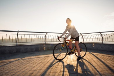 young woman riding a bicycle in the morning city at sunrise. urban life concept