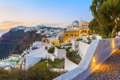 beautiful alleys of the famous fira town after sunset at twilight time.tourists rest and relax in the cozy cafes and restaurants,enjoying the views.santorini (thira) island.cyclades.greece.europe.
