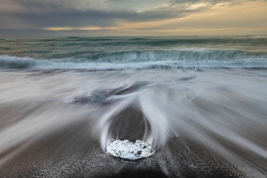 ice cube with smooth wave at black sand beach iceland during sunrise