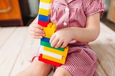 little girl in red dress sitting on the wooden floor and playing . top view