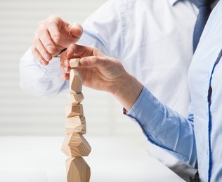 business people building wooden tower (japanese game tumi-ishi), illustrating concept of business success, cooperation, achievement and self-control
