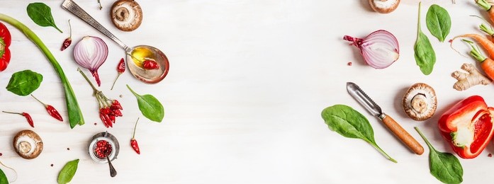 healthy food background with various vegetables ingredients, spoon with oil and peeler, top view