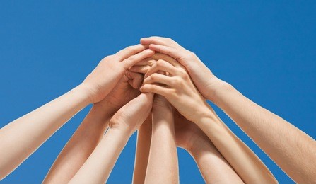 successful team: many hands holding together  on sky background