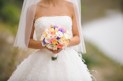 bride holding flowers in park