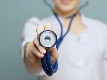 medical doctor woman   on a blue background holding a stethoscope focus on the stethoscope