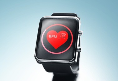 modern technology, object, health care and media concept - close up of black smart watch showing red heart beat icon on screen